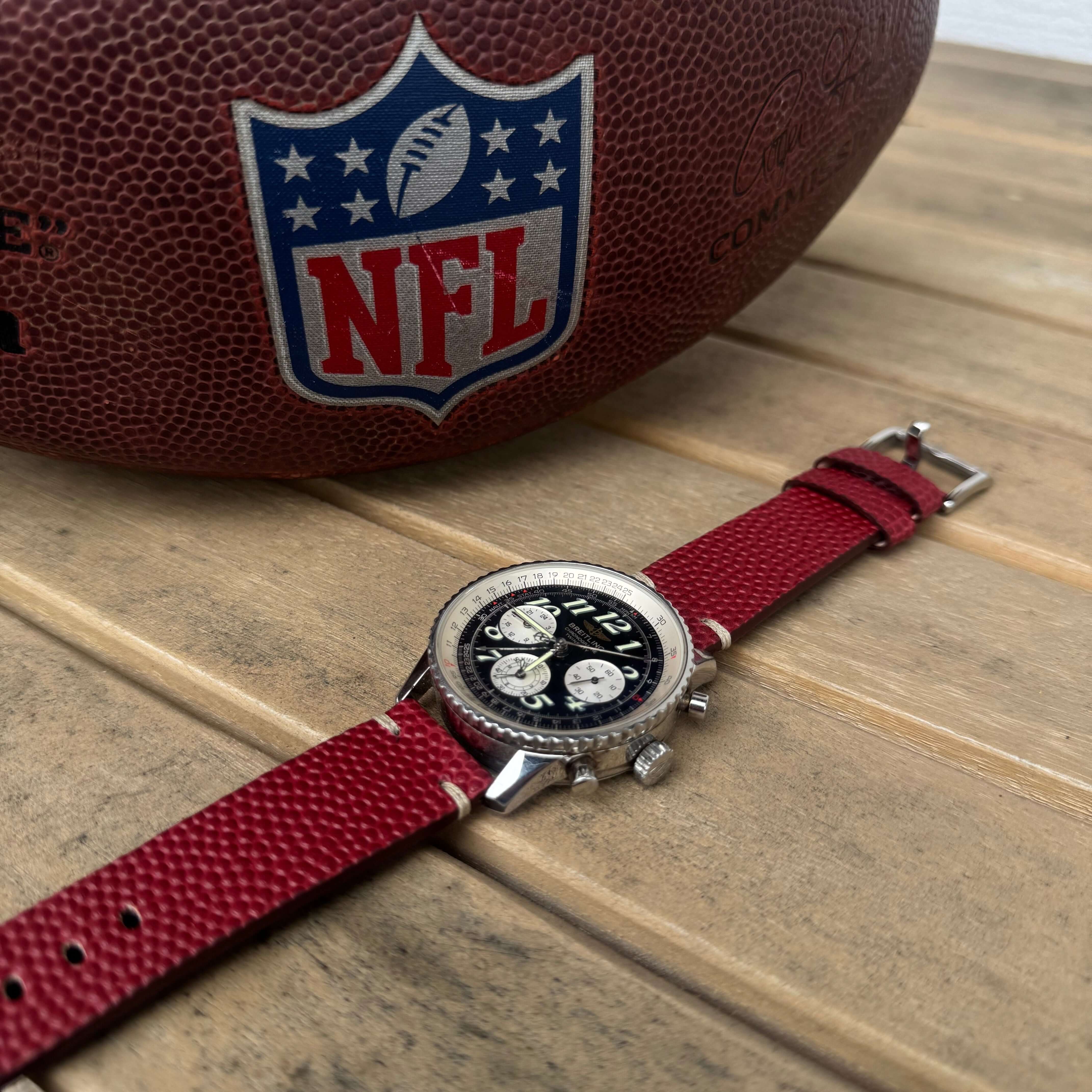 Touchdown – Uhrenarmband handgefertigt aus original Horween Footballleder an einer Breitling Navitimer Uhr neben einem NFL Ball