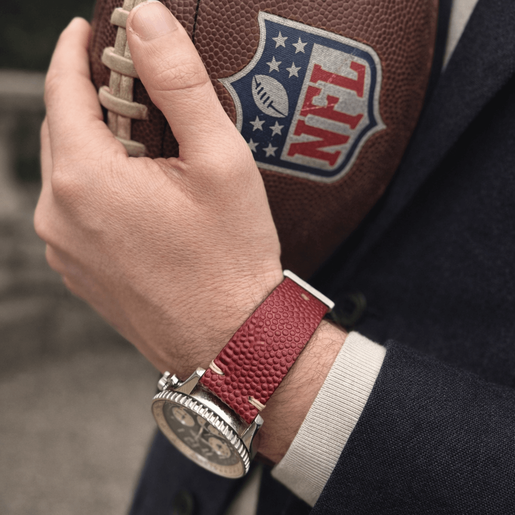 Touchdown – Uhrenarmband handgefertigt aus original Horween Footballleder, passend für Breitling Navytimer Uhr, mit NFL-Logo im Hintergrund.