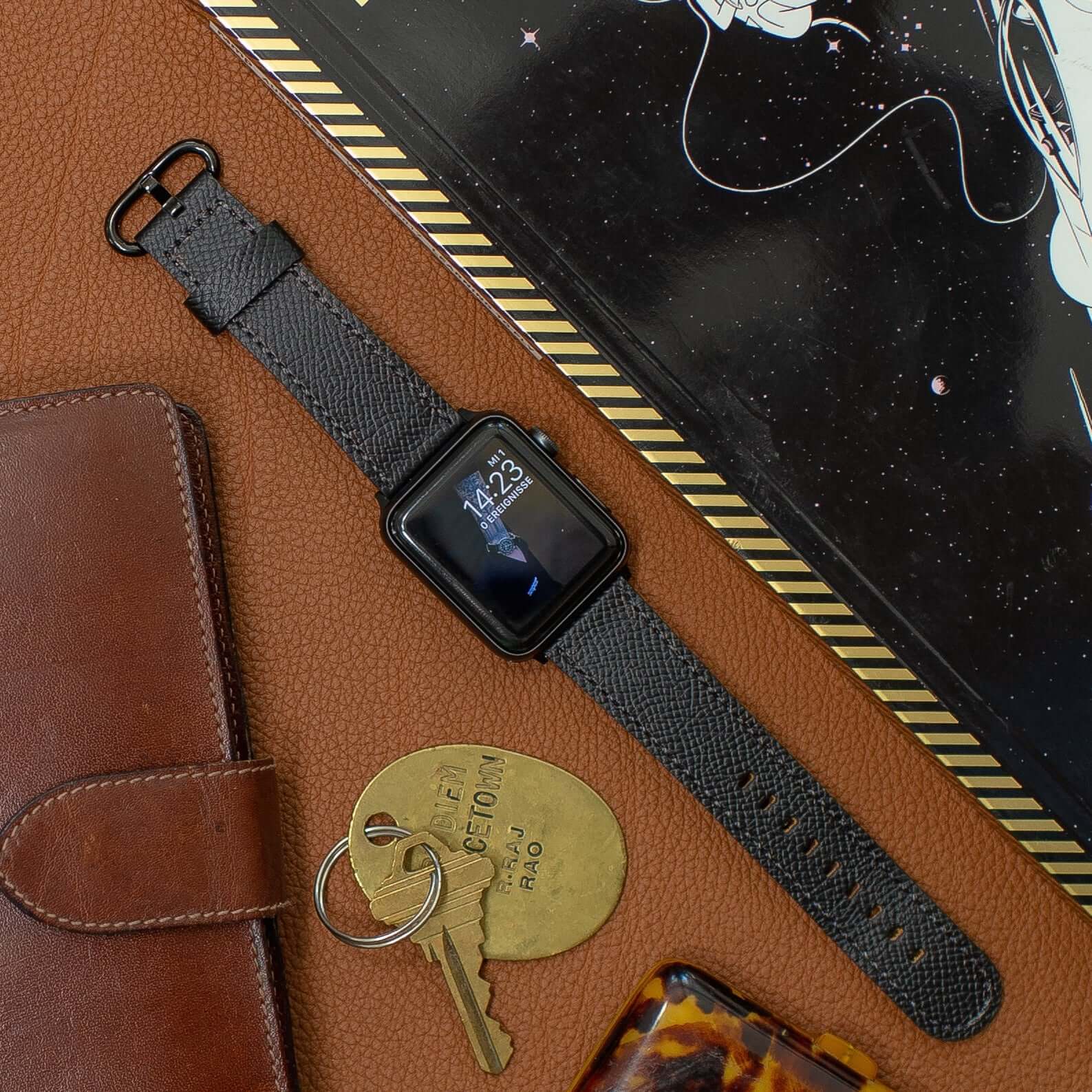 Luxuriöses Apple Watch Lederarmband Damen Cupertino Schwarz aus Epsom Kalbleder, stilvoll und strapazierfähig, auf Ledertisch mit Accessoires.