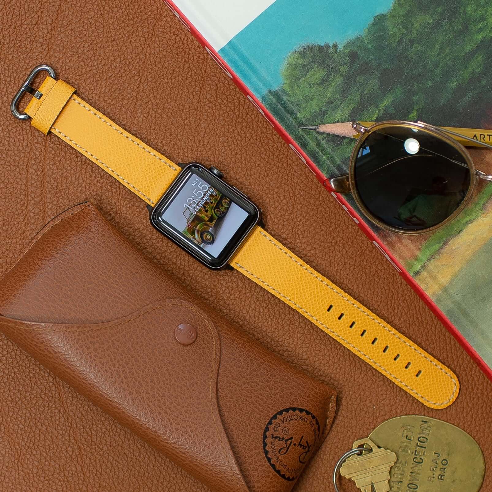 Luxuriöses Apple Watch Lederarmband Damen Cupertino Gelb auf Lederuntergrund mit Sonnenbrille und Buch, hochwertiges Epsom Leder.