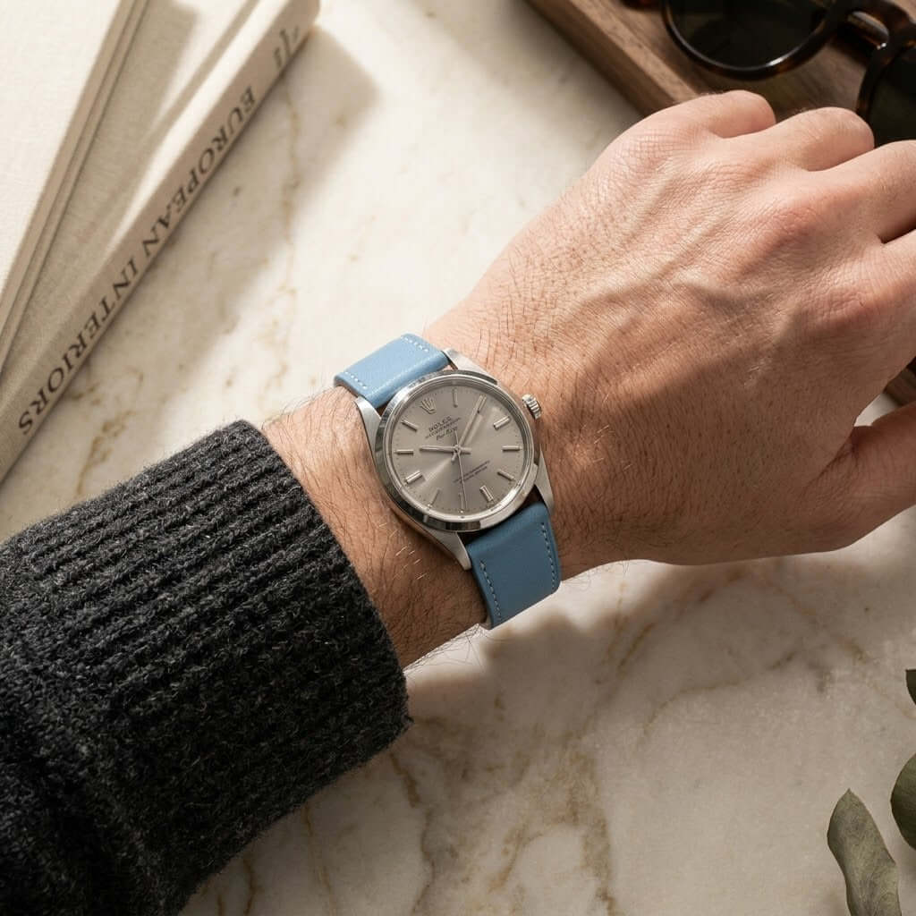 Swift – Uhrenarmband aus italienischem Swift Leder an einer Hand, elegant auf einem Marmor Tisch.