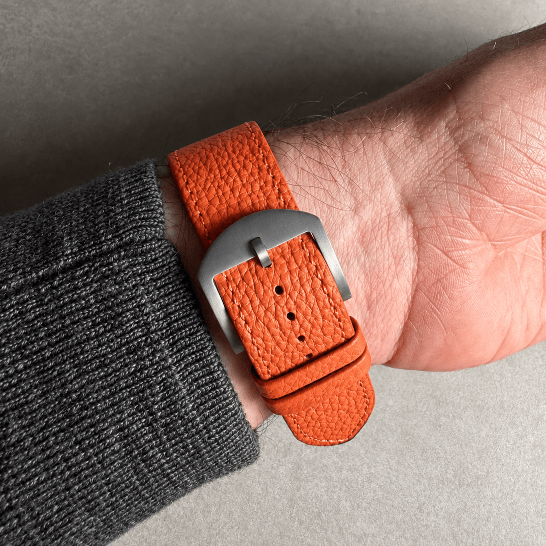 Oranges Lederarmband für Apple Watch aus Togoleder am Handgelenk, leuchtendes Orange, stilvolle Silberschnalle.