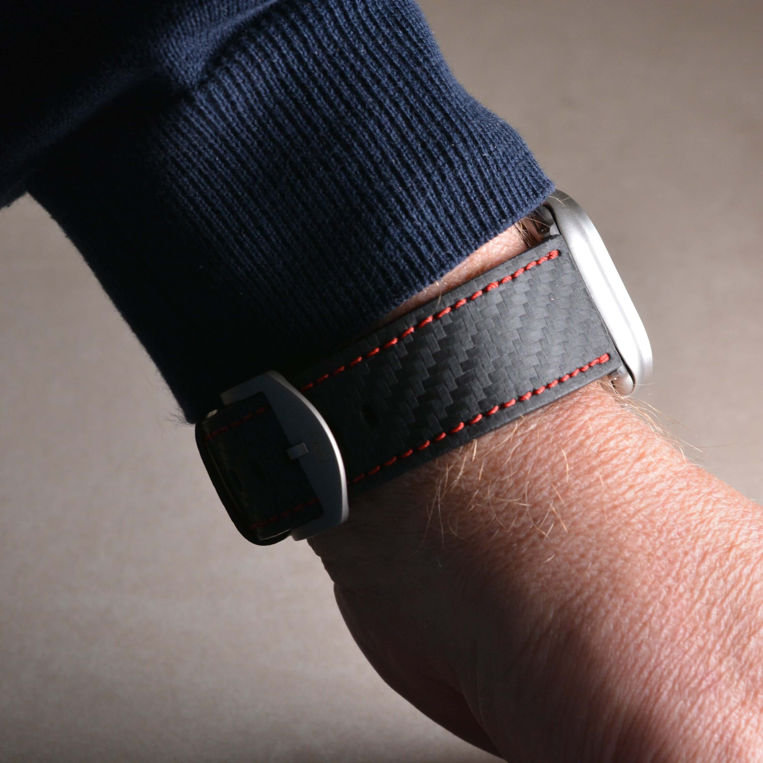 Bergwerk Carbon Rot – Apple Watch Band mit hochwertiger LederCarbon-Struktur auf einer Hand getragen, Detailansicht.