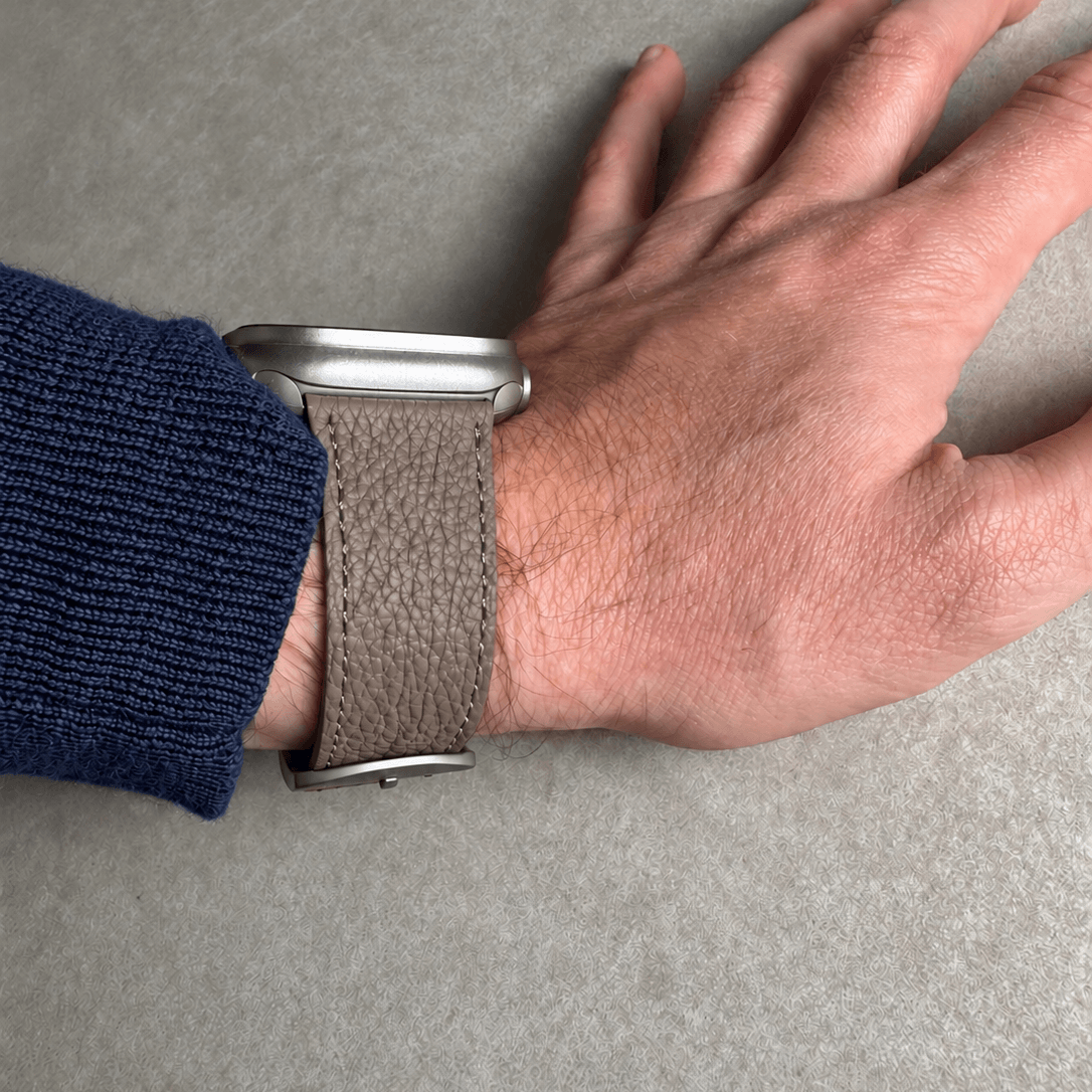 Taupes Lederarmband für Apple Watch aus Togoleder, stilvoll am Handgelenk getragen.
