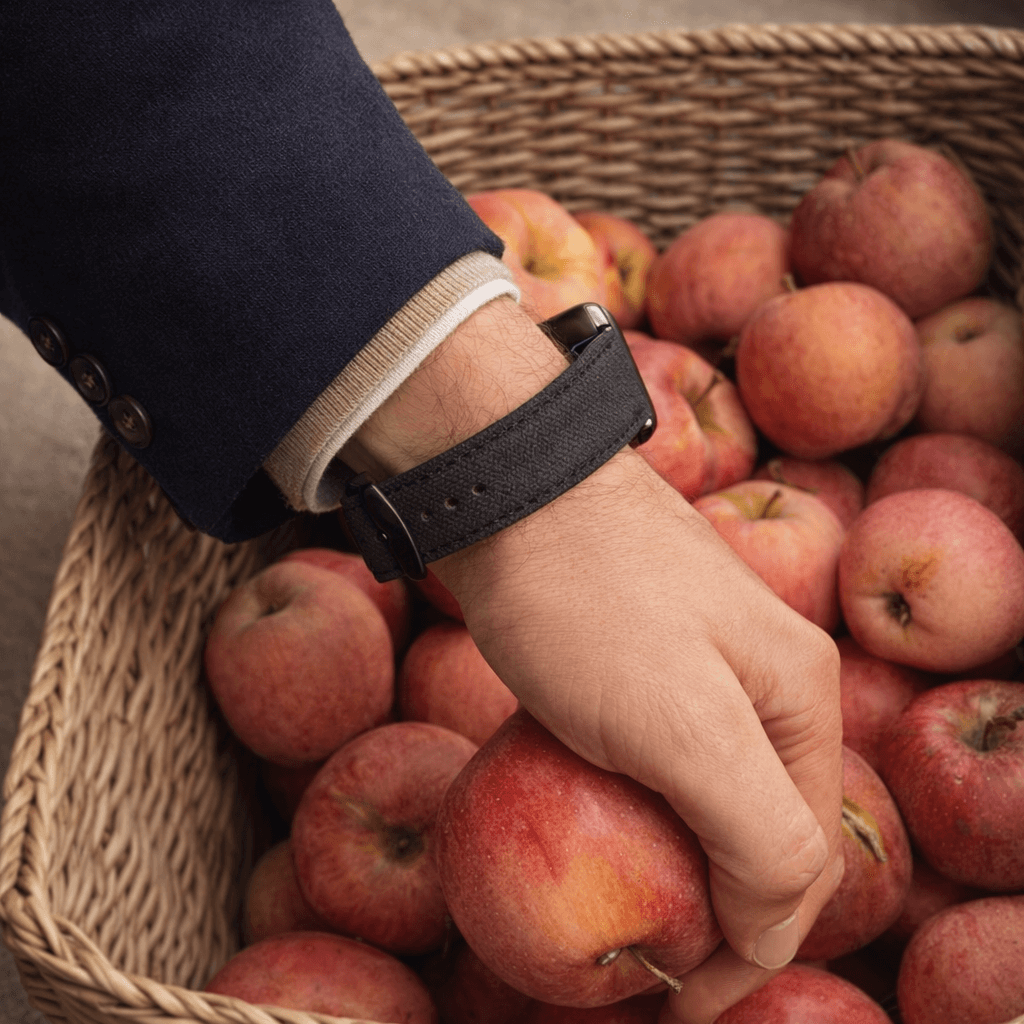 Schwarzes Canvas Apple Watch Band Baumwolle an Hand, die rote Äpfel aus einem Korb nimmt - stilvoll und robust.