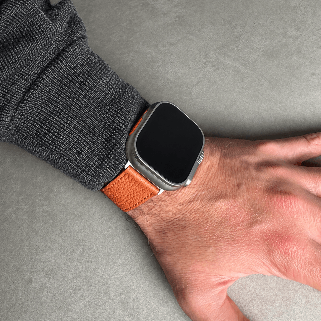 Oranges Lederarmband für Apple Watch aus Togoleder in der Nahaufnahme an einem Handgelenk.