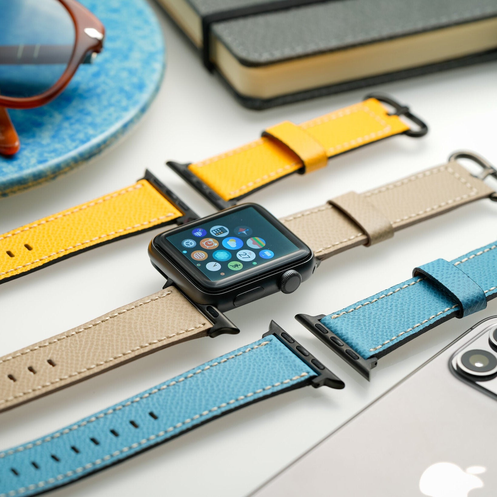 Luxuriöses Apple Watch Lederarmband in Hellblau, Beige und Gelb auf Schreibtisch, stilvolles Accessoire für Damen