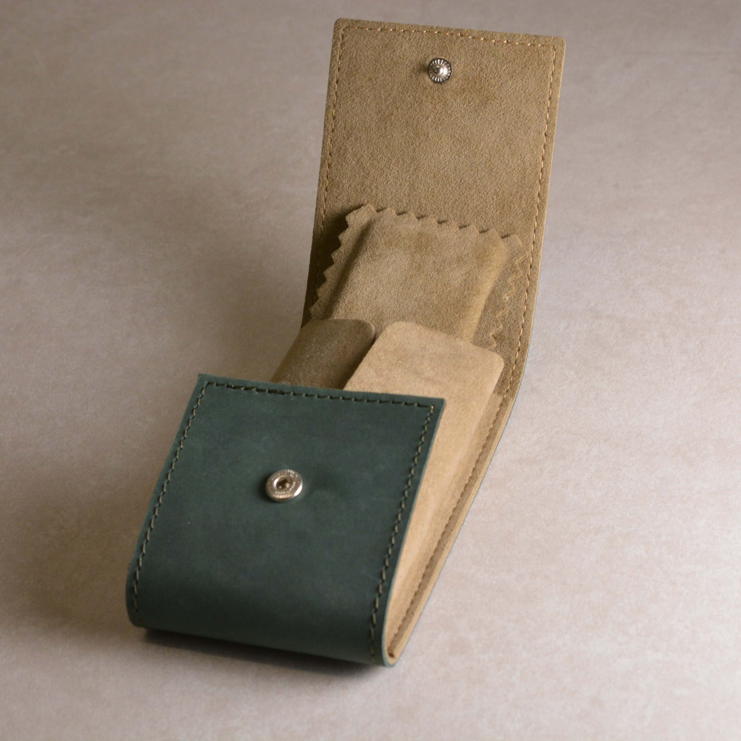 Elegantes Uhrenetui Leder Grün für 1 Uhr in exquisite Dunkelgrün geöffnet auf hellem Hintergrund, perfekt für Armbanduhrenliebhaber.