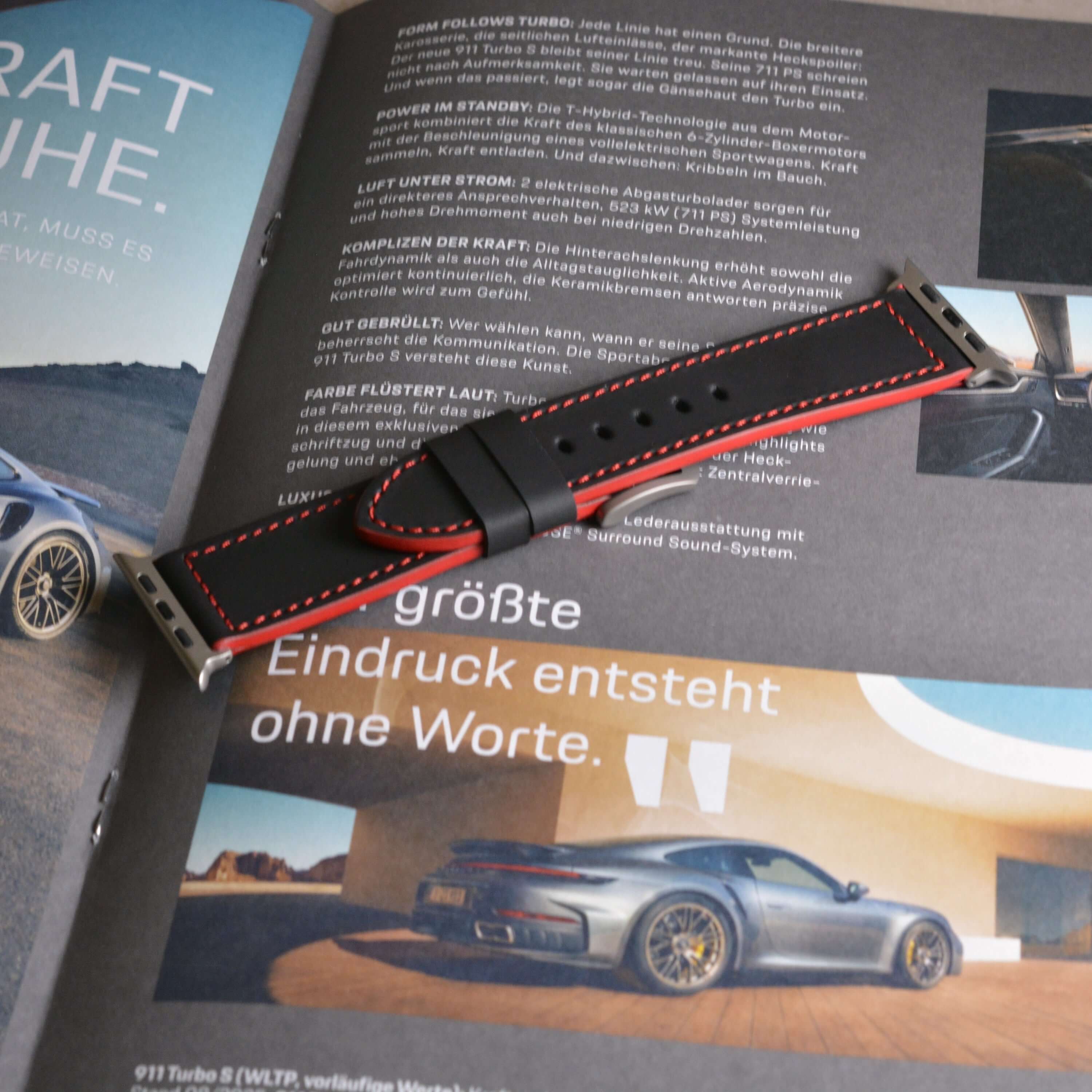 Das Apex – Apple Watch Armband aus schwarzem Motorsport-Kalbleder, inspiriert vom Porsche 911 GT3 RS, auf Lifestyle-Magazin liegend.