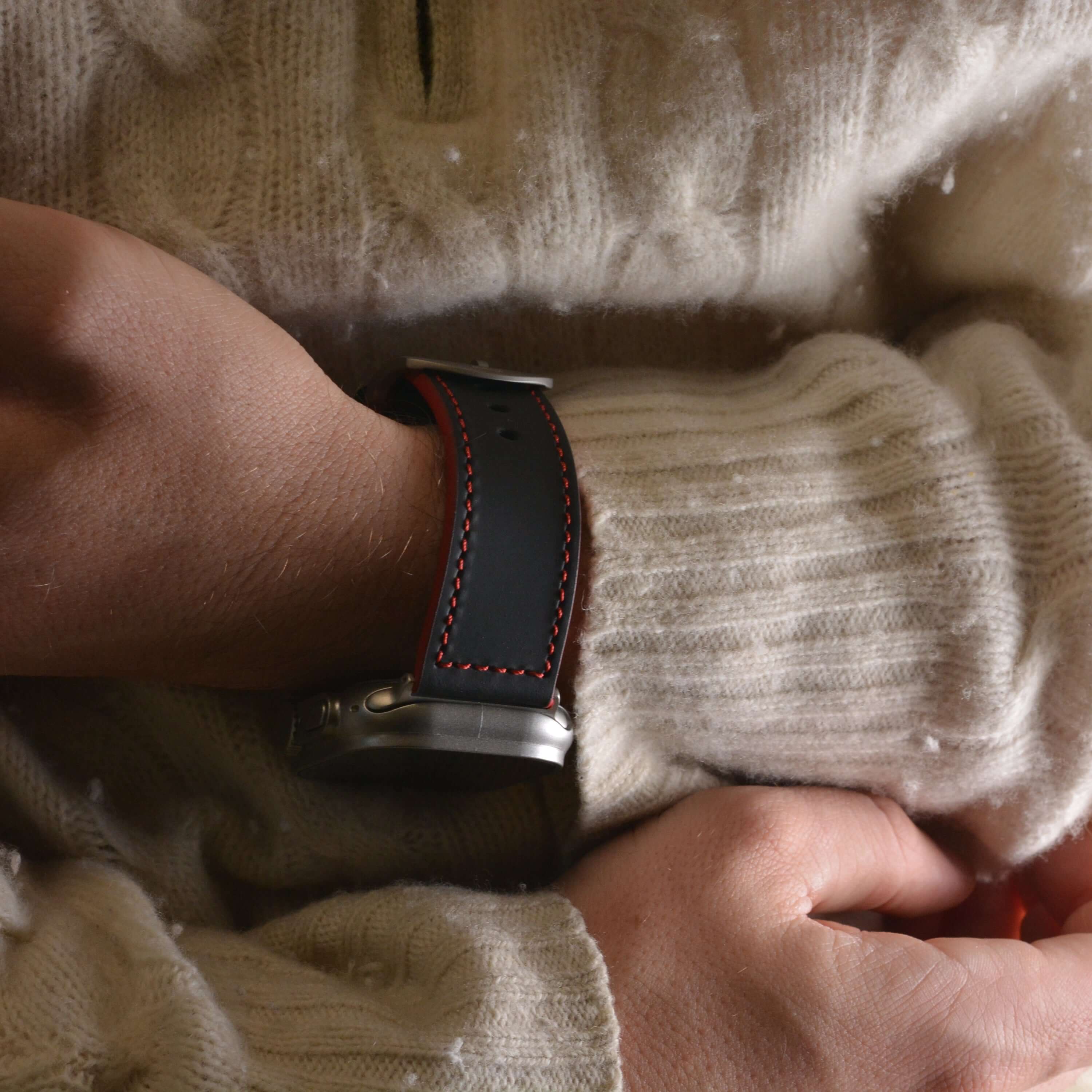 Das Apex – Apple Watch Armband aus schwarzem Motorsport-Kalbleder mit roten Nähten, inspiriert vom Porsche 911 GT3 RS, getragen am Handgelenk.