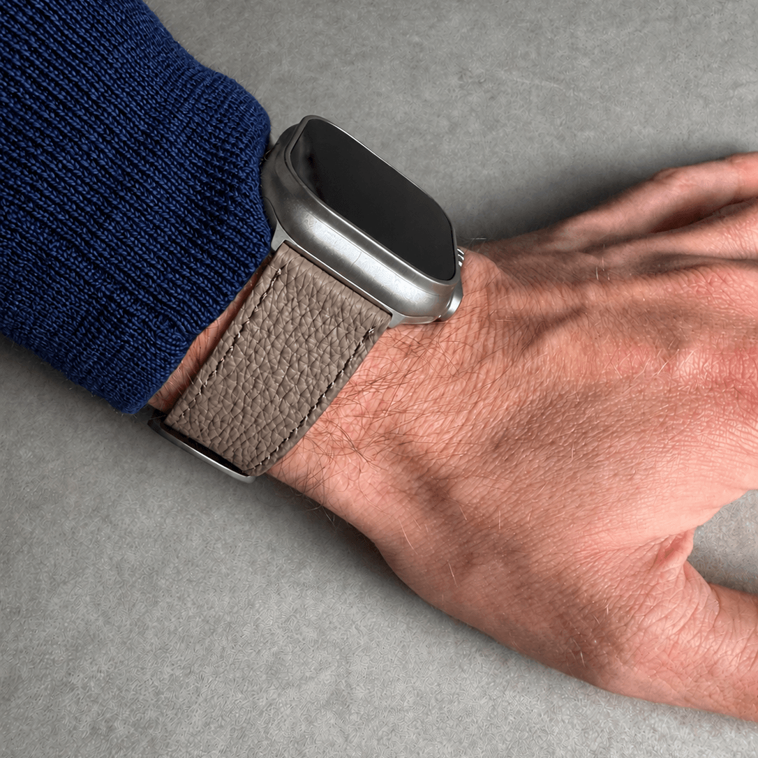 Taupes Lederarmband für Apple Watch aus Togoleder, tragend an Handgelenk mit silberner Uhr.