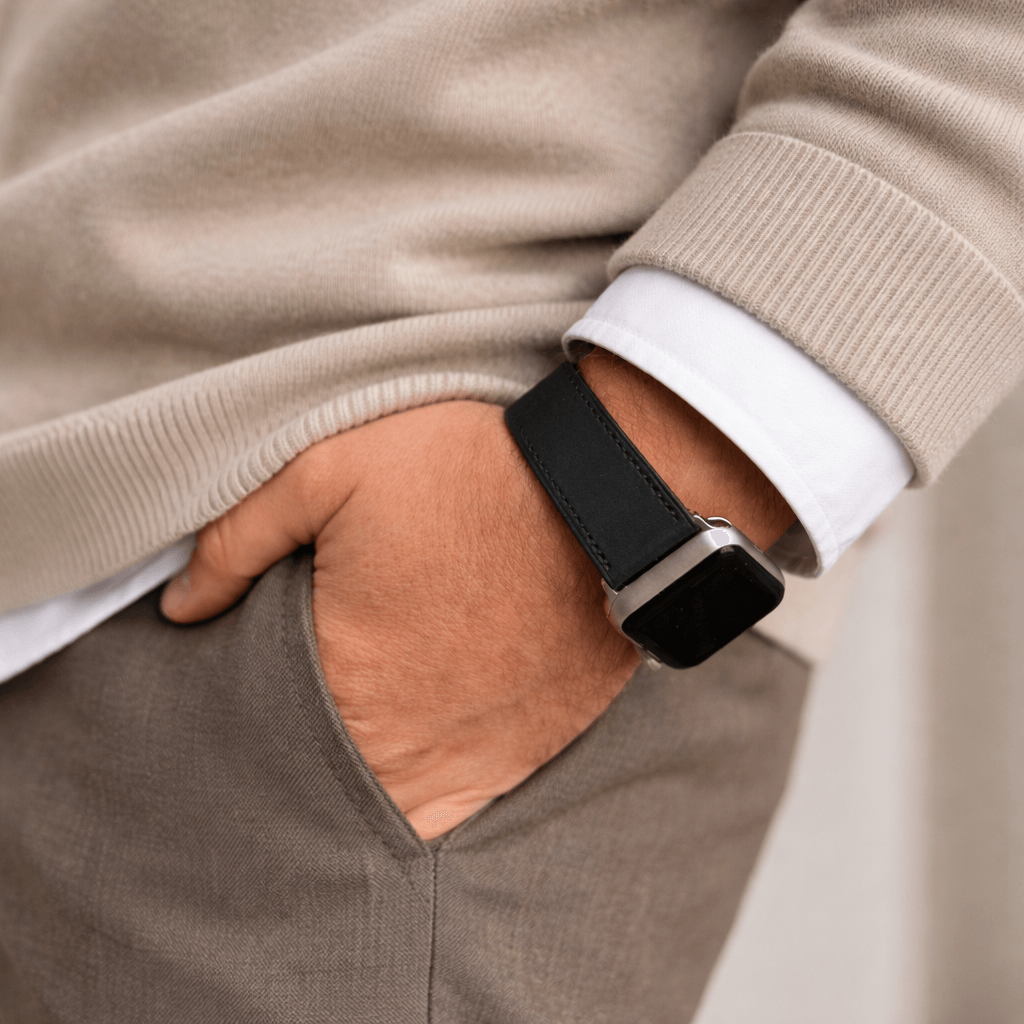 Mountain Apple Watch Lederarmband – Schwarz am Handgelenk eines Mannes, elegant mit beigefarbener Kleidung kombiniert.