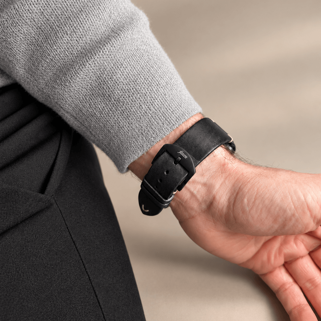 Hunter Apple Watch Armband Leder Schwarz am Handgelenk eines Mannes, kombiniert mit grauem Pullover.