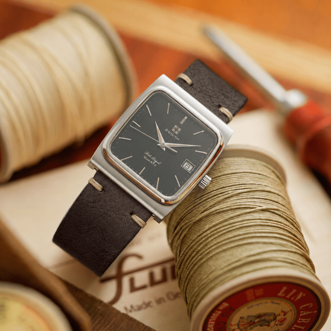 Zenith Chronograph with a handcrafted vegetable-tanned leather watch strap from Tuscany, Italy, featuring fine hand stitching on a rustic wooden workbench surrounded by leathercraft tools.