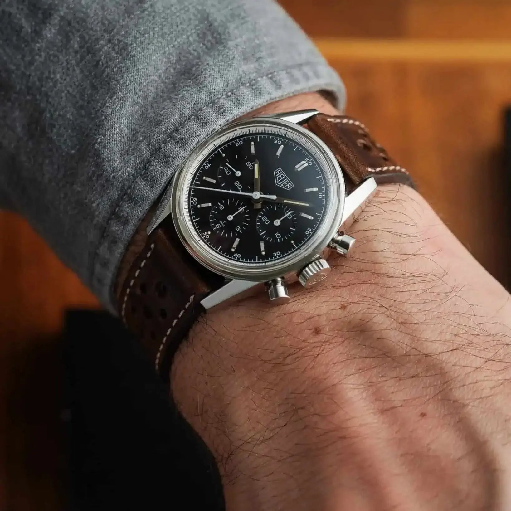 Mann trägt Rallye Uhrenarmband Aus Dublin Leder mit schwarzem Zifferblatt auf Holzuntergrund, klassischer Motorsport-Stil.