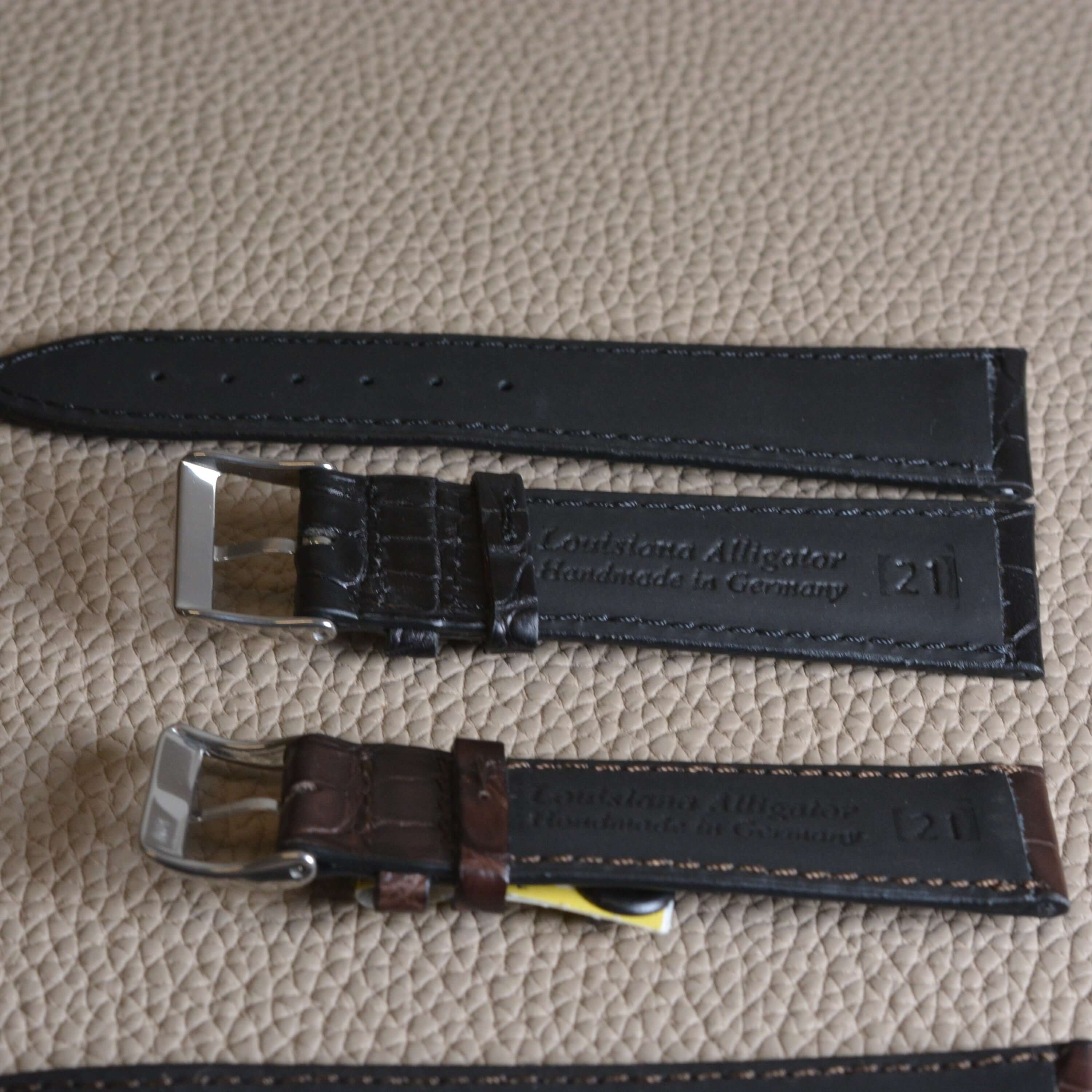 Louisiana Alligator Uhrenarmband 21mm in black and brown on textured leather surface, showcasing luxury craftsmanship.