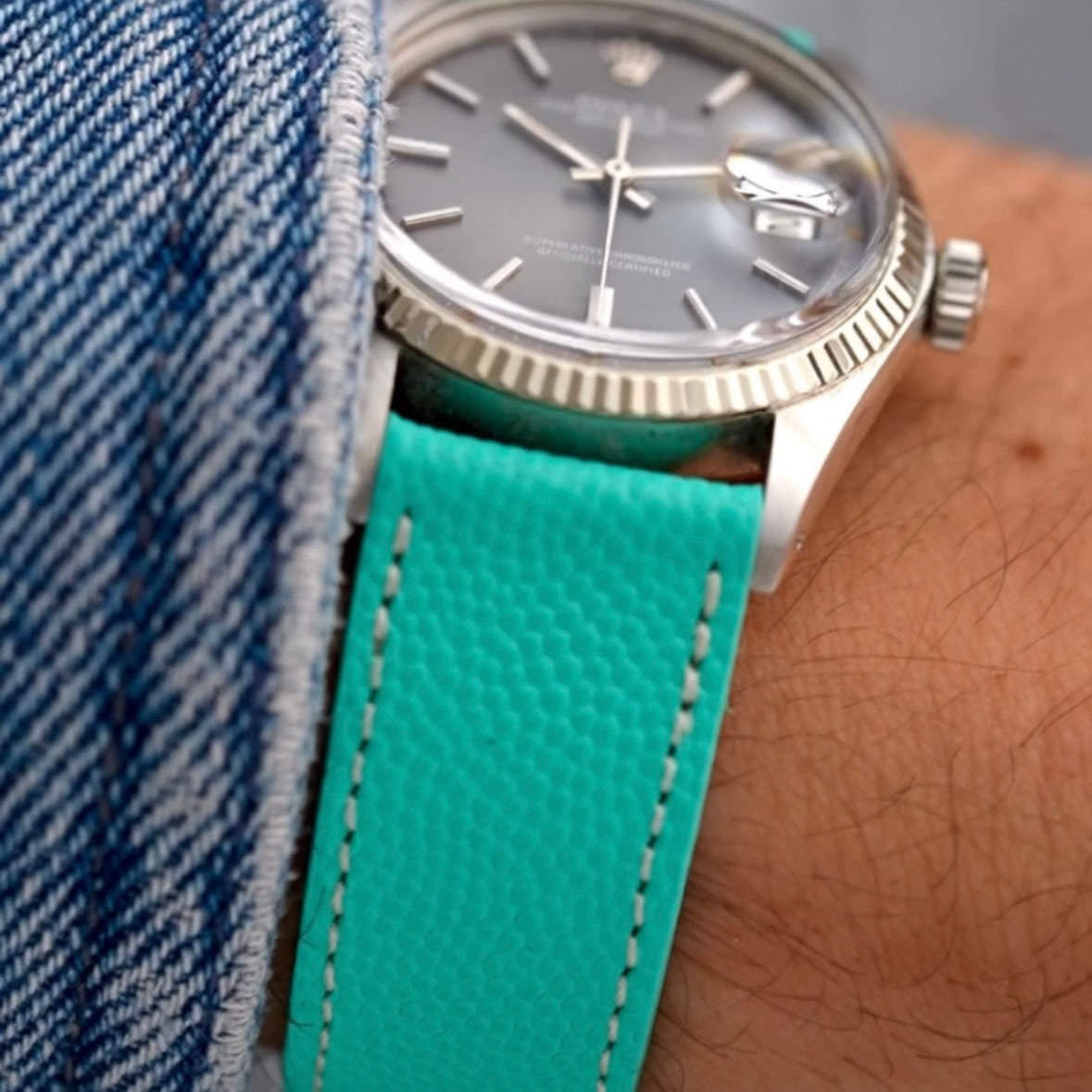 Nahaufnahme einer hochwertigen Uhr mit grauen Ziffern und turquoise Uhrenarmband, das perfekt an einem Handgelenk sitzt. Hochwertig, uhrenarmband hochwertig.