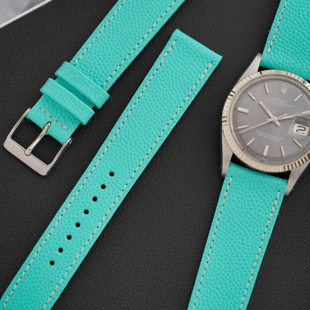 Uhrenarmband Kaviarleder in turquoise, zusammen mit einer eleganten Uhr auf einem dunklen Hintergrund, ideal für stilvolle Outfits. Hochwertig, uhrenarmband hochwertig.