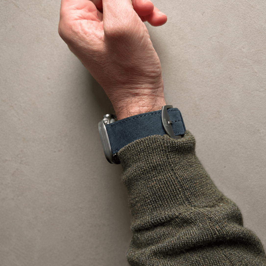 Alcantara – Apple Watch Armband in Dunkelgrau getragen an einem Handgelenk mit grünem Pullover.
