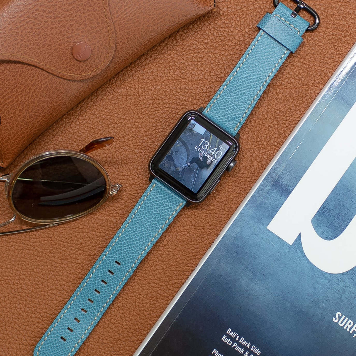 Luxuriöses Apple Watch Lederarmband Damen Cupertino Hellblau neben Sonnenbrille und Zeitschrift auf Lederoberfläche