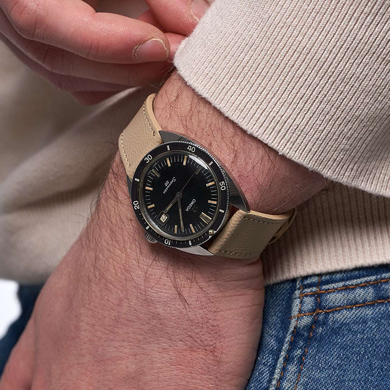 Beiges Kaviarleder Uhrenarmband am Handgelenk an einer Omega Seamaster – Detailaufnahme eines beigen Kaviarleder Uhrenarmbands, das an einer Omega Seamaster Uhr getragen wird. Das hochwertige Leder verleiht der Uhr einen eleganten, luxuriösen Look und sorgt gleichzeitig für maximalen Tragekomfort.