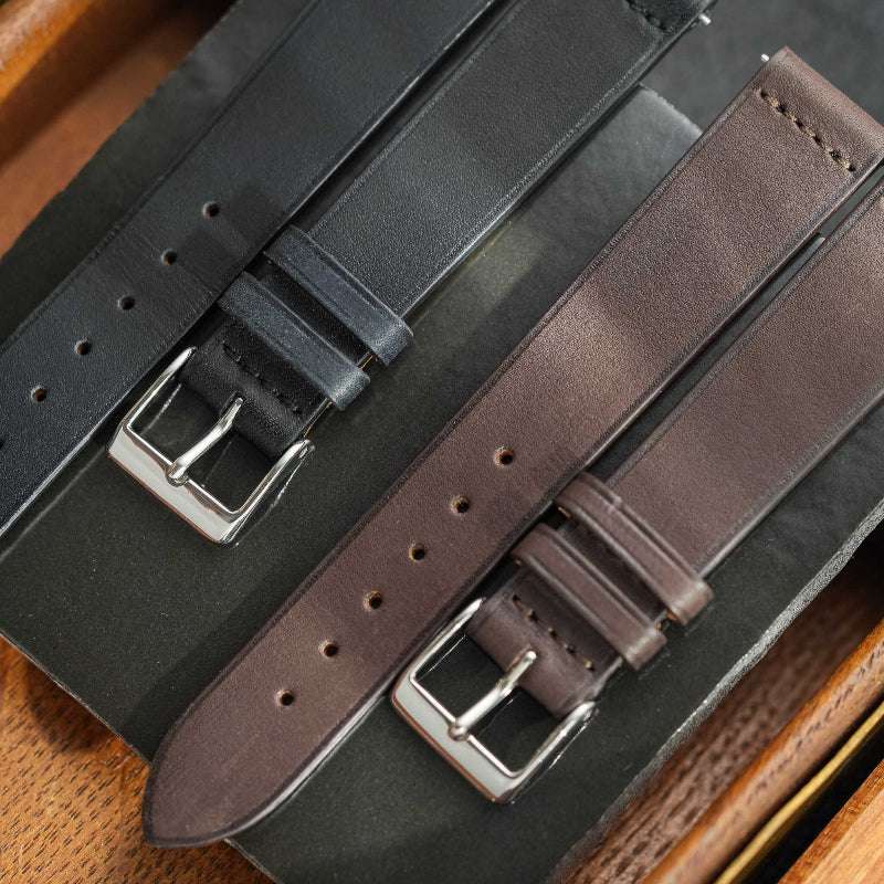 Dunkelbraunes Barenia Glattleder Uhrenarmband neben schwarzem Uhrenarmband – Detailaufnahme von zwei hochwertigen Lederarmbändern, einem dunkelbraunen Barenia Glattleder und einem schwarzen Uhrenarmband, ideal für elegante Zeitmesser