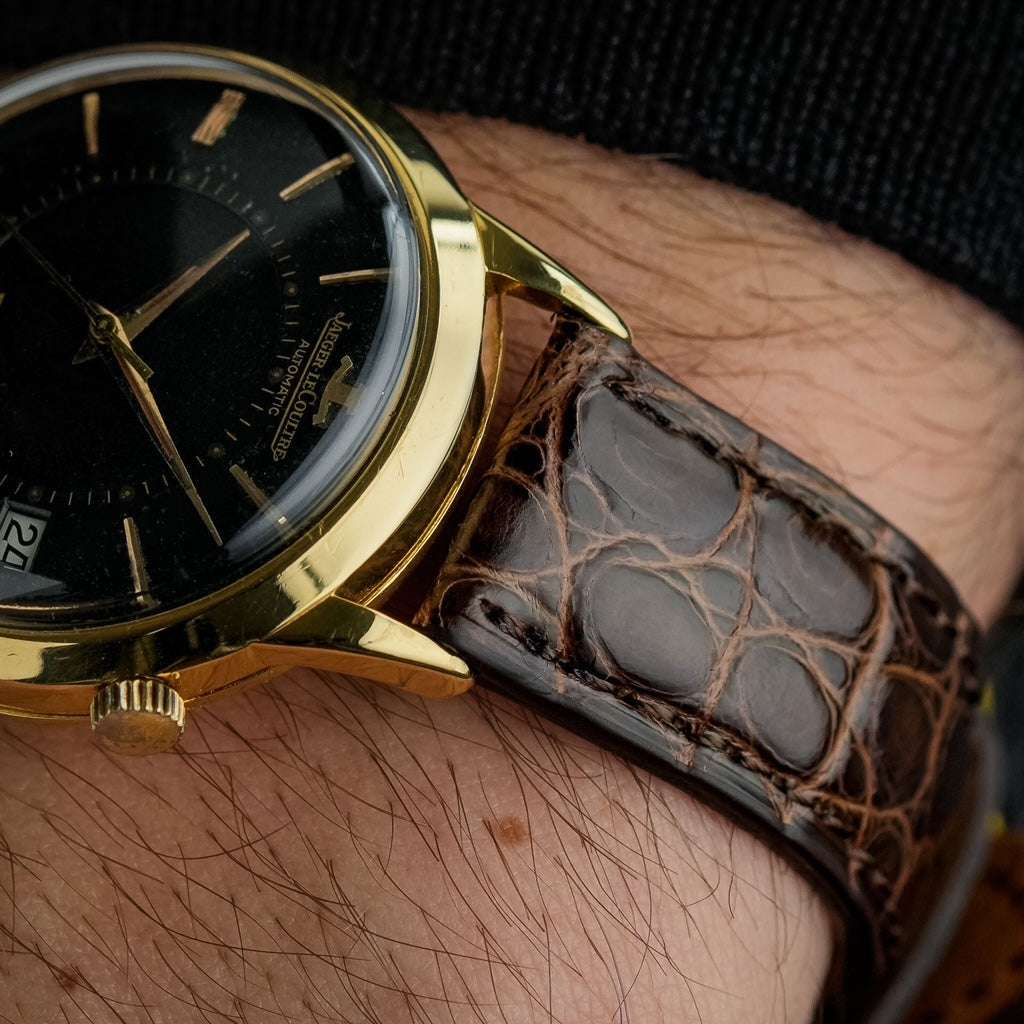 Dunkelbraunes glänzendes echtes Alligator Uhrenarmband an Jaeger Le Coultre Memovox in Schwarz/Gold – Detailaufnahme der Uhr mit luxuriösem, strapazierfähigem Alligatorlederarmband, ideal für elegante und sportliche Zeitmesser