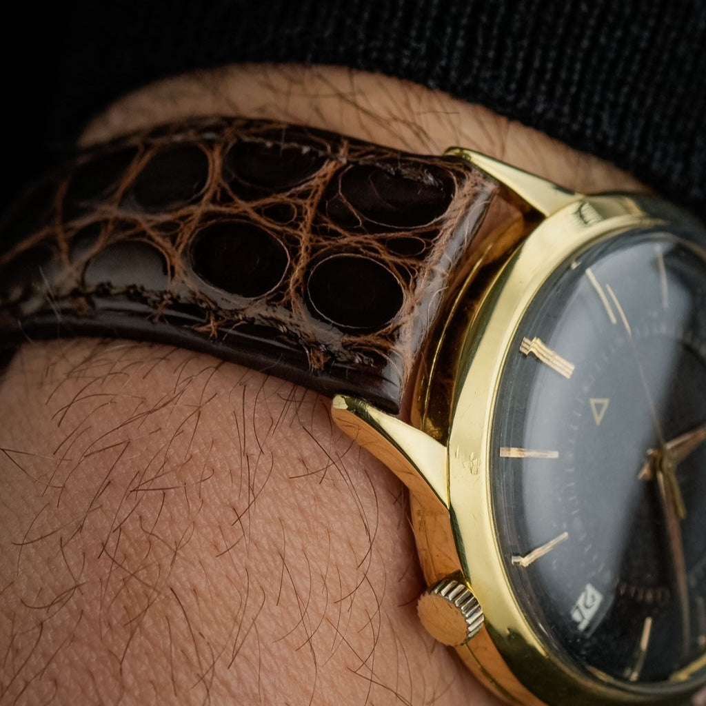 Dunkelbraunes glänzendes echtes Alligator Uhrenarmband an Jaeger Le Coultre Memovox in Schwarz/Gold – Seitenansicht der Uhr mit strapazierfähigem, glänzendem Alligatorlederarmband, Made in Germany, für luxuriöse und sportliche Uhren