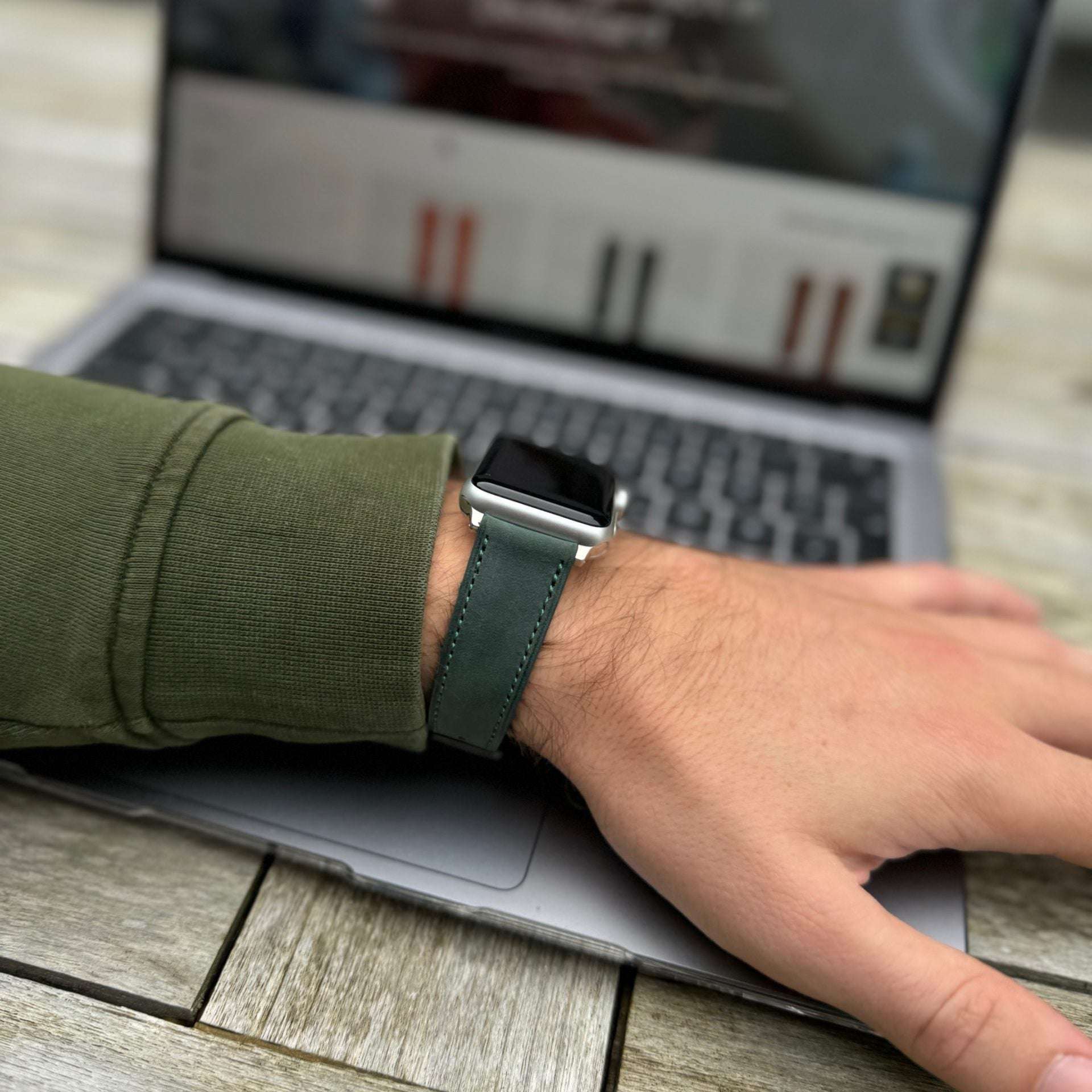 Dunkelgrünes Nubukleder-Armband für Apple Watch am Handgelenk – Frontansicht mit grünem Pullover