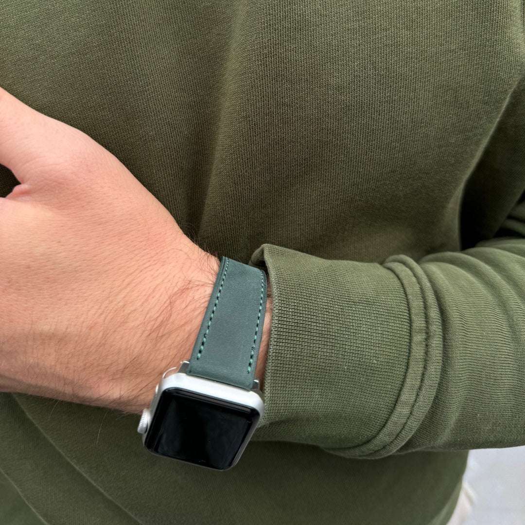 Dunkelgrünes Nubukleder-Armband für Apple Watch am Handgelenk – Schrägansicht mit grünem Pullover, dezente Eleganz