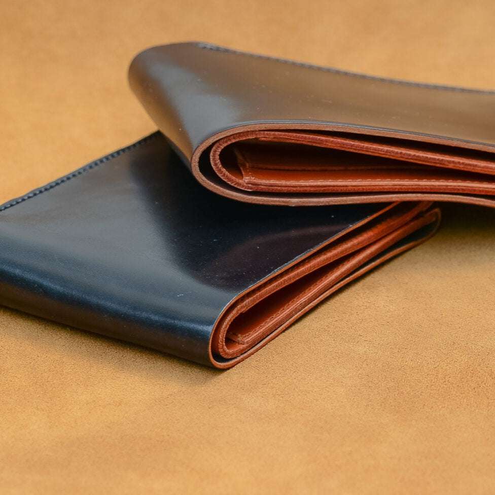 Zwei Geldbörsen aus Horween Shell Cordovan in Schwarz und Bordeaux, nebeneinander präsentiert, luxuriöse Accessoires mit edler Verarbeitung