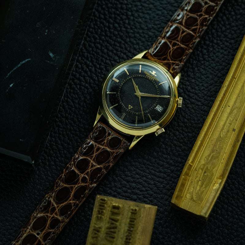 Dunkelbraunes glänzendes echtes Alligator Uhrenarmband an Jaeger Le Coultre Memovox in Schwarz/Gold – Seitenansicht der Uhr mit strapazierfähigem, glänzendem Alligatorlederarmband, Made in Germany, für luxuriöse und sportliche Uhren