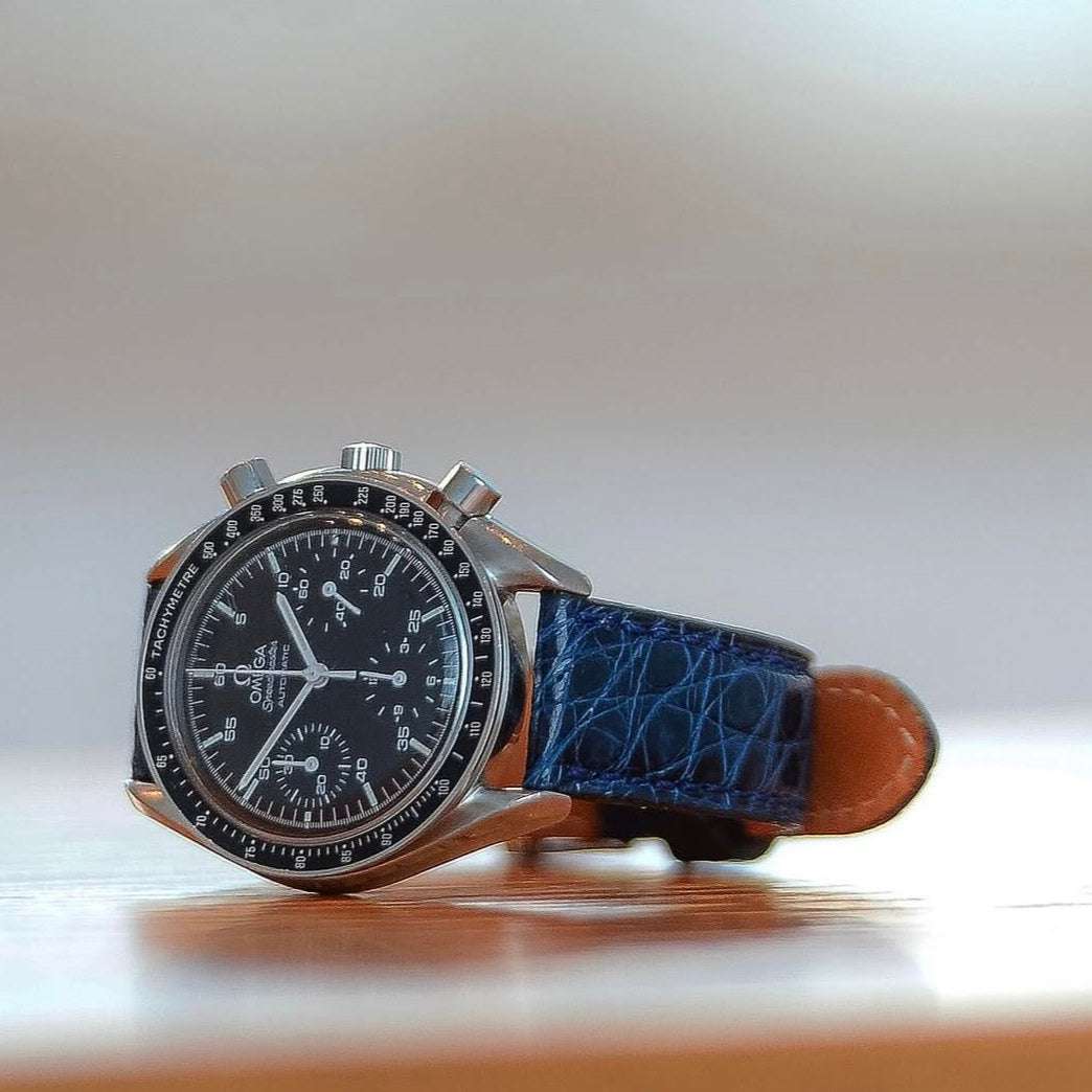 Glänzendes blaues echtes Alligator Uhrenarmband an Omega Speedmaster – Detailaufnahme der Uhr mit hochwertigem, glänzendem Alligatorlederarmband, luxuriös und strapazierfähig, perfekt für anspruchsvolle Zeitmesser