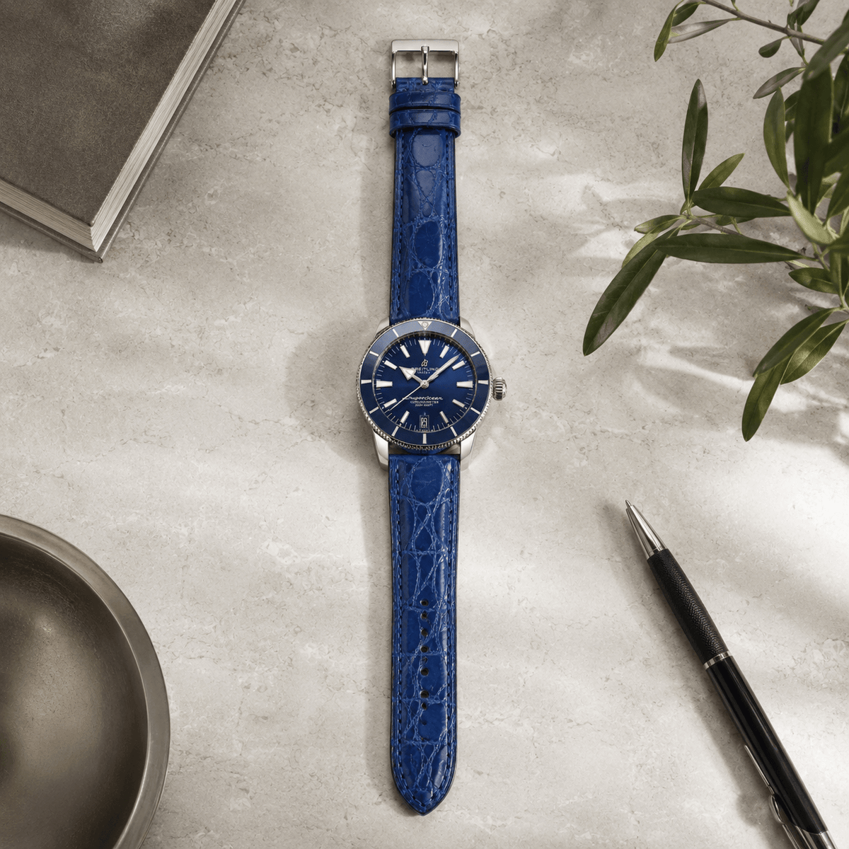 Shiny – Uhrenarmband aus glänzendem Kaimanleder an elegantem Zifferblatt auf Tischplatte.