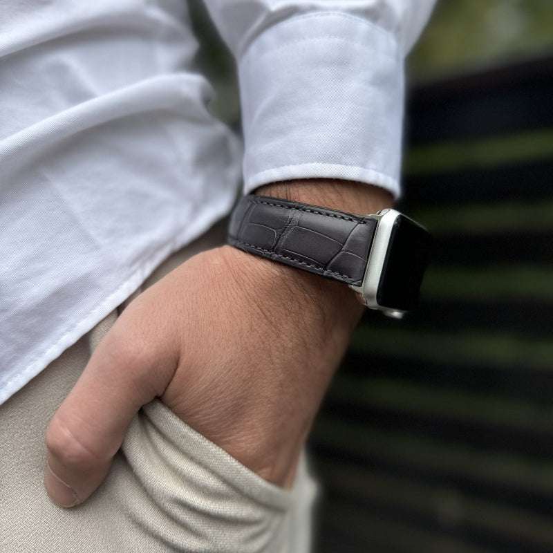 Graues Echt-Alligator-Armband für Apple Watch – Seitenansicht am Handgelenk auf beiger Hose mit weißem Hemd im Hintergrund