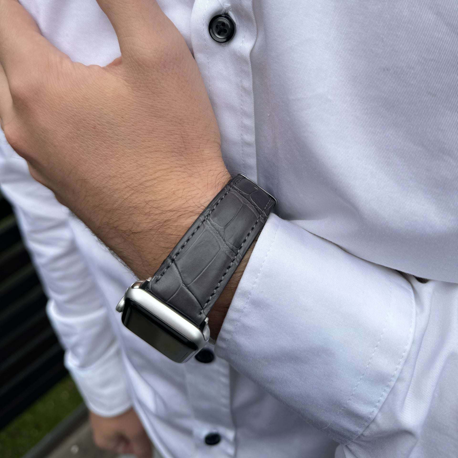 Graues Echt-Alligator-Armband für Apple Watch am Handgelenk – Elegantes Design auf beiger Hose mit weißem Hemd im Hintergrund