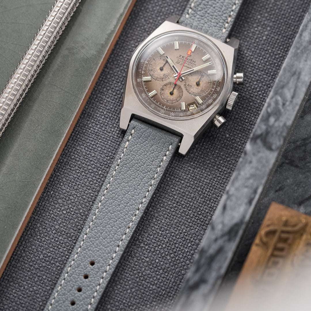 Graues Ziegenleder Uhrenarmband an einer Zenith El Primero in drei Varianten – Detailaufnahme des grauen Ziegenlederarmbands, das an einer Zenith El Primero getragen wird, zusammen mit zwei oliven Ziegenlederbändern, die als Vergleich daneben liegen. Die verschiedenen Farben und Materialien bieten eine stilvolle Auswahl für anspruchsvolle Uhrenliebhaber.