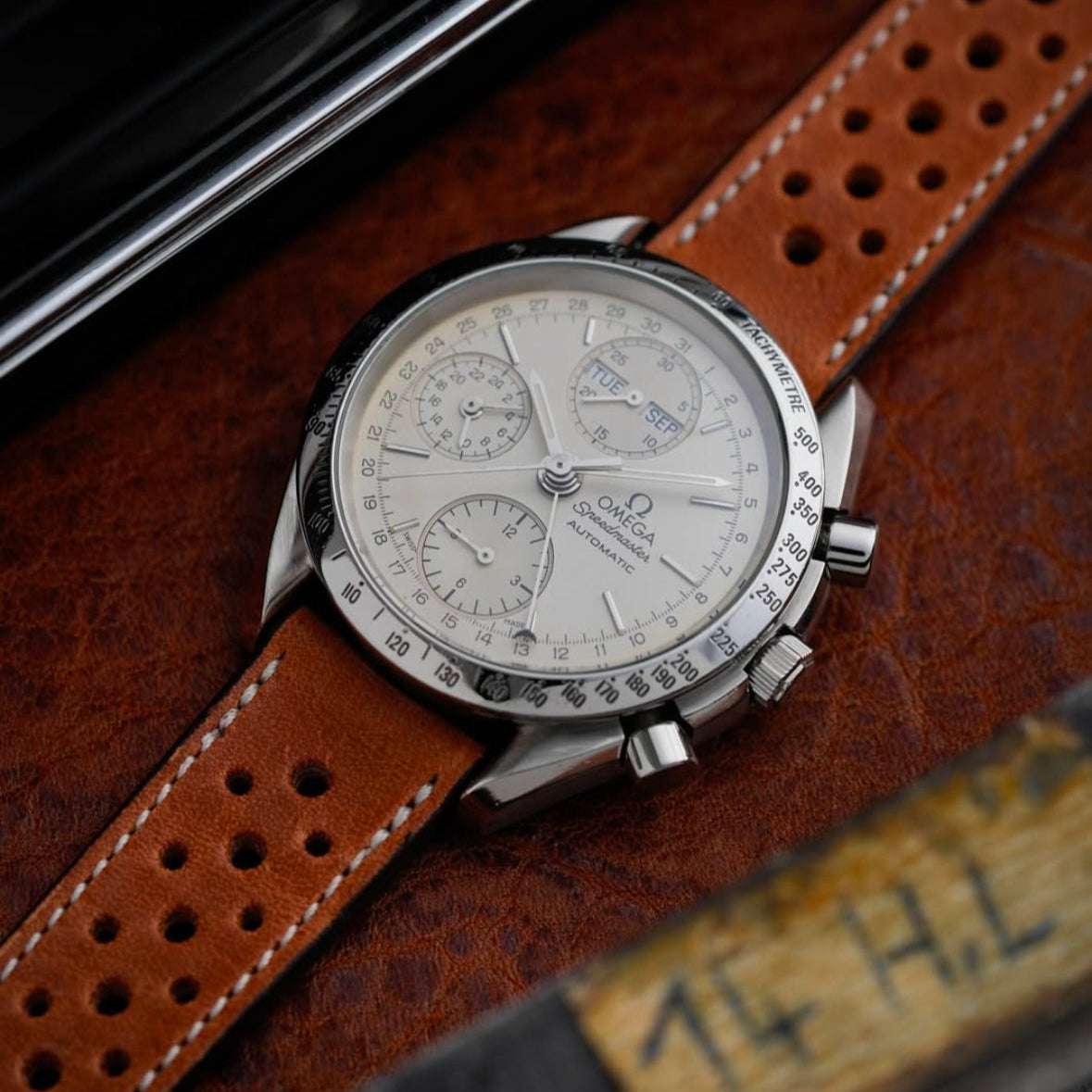 Hellbraunes Horween Dublin Leder Racing Uhrenarmband an Omega Speedmaster White Dial – Seitenansicht der Omega Speedmaster White Dial Uhr mit strapazierfähigem, hellbraunem Horween Dublin Lederarmband, das für seine Langlebigkeit und exklusive Verarbeitung bekannt ist