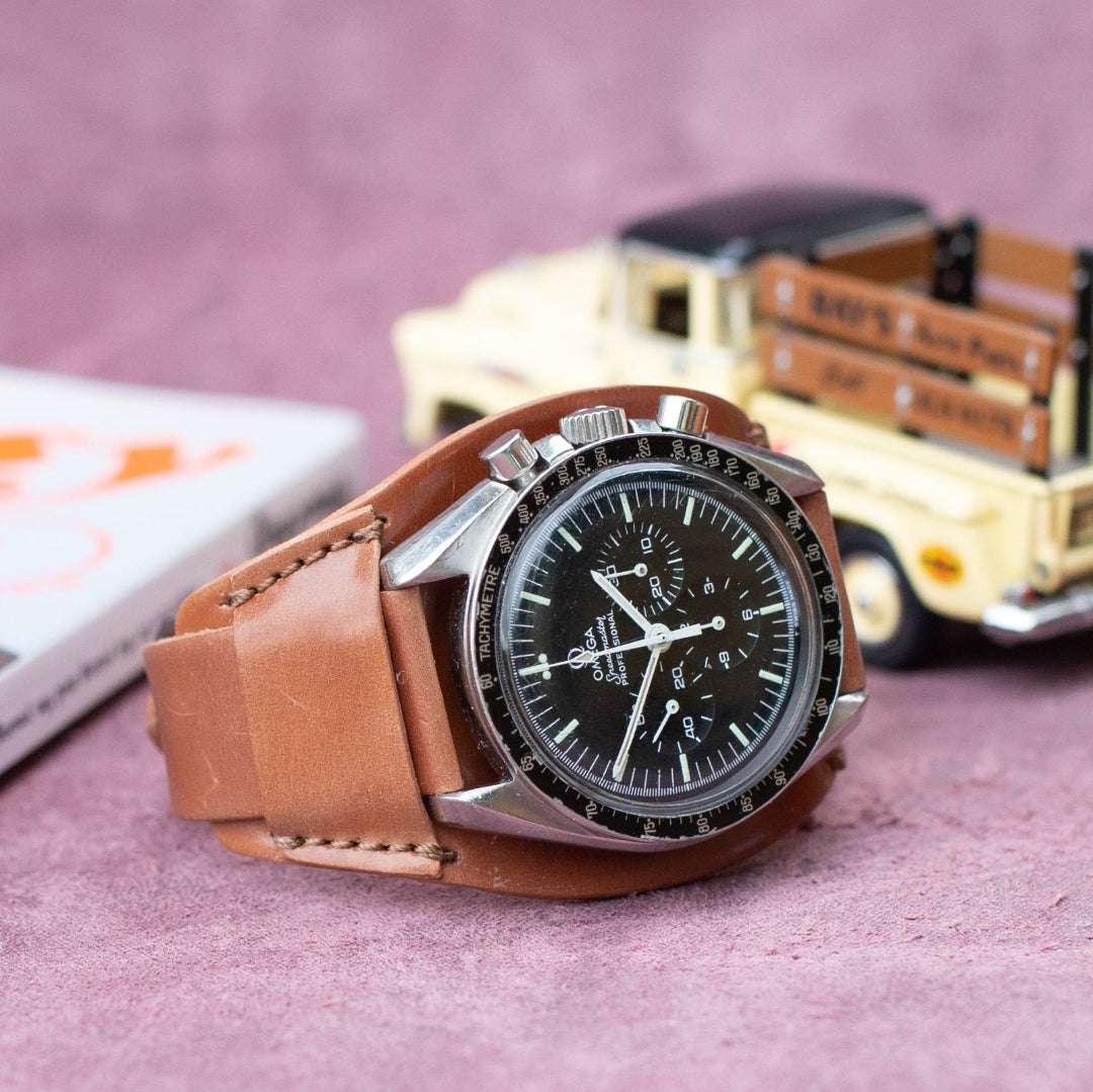 Horween Shell Cordovan Unterlagen Uhrenarmband in Whisky an Omega Speedmaster – Seitenansicht der Uhr mit hochwertigem, strapazierfähigem Shell Cordovan Unterlagen Uhrenarmband, handgefertigt in Deutschland, für sportliche und luxuriöse Uhren