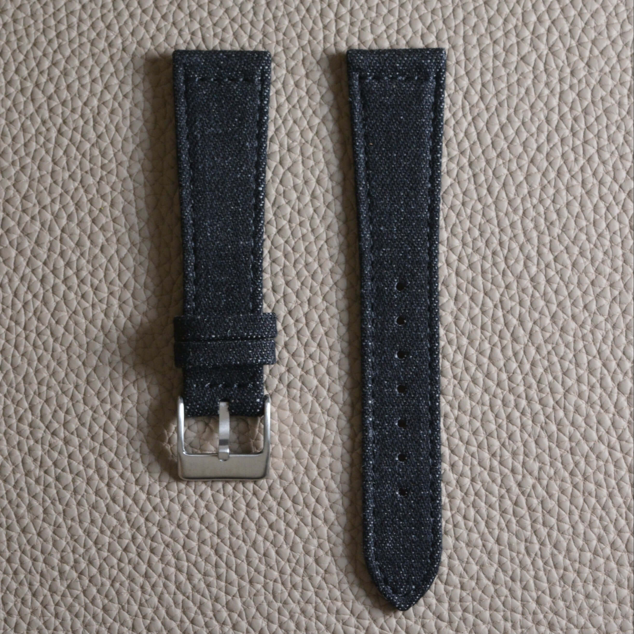 Jeans Uhrenarmband aus japanischem Denim, edel designt mit schwarzem Kalbleder gefüttert, präsentiert auf texturiertem Untergrund