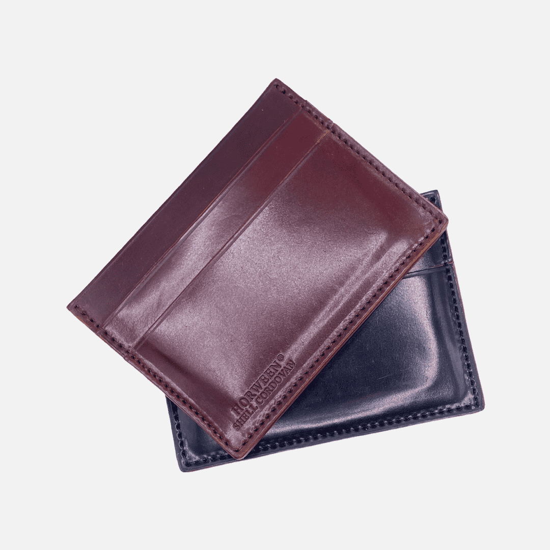 Zwei Kreditkartenetuis aus Horween Shell Cordovan, eines in Schwarz und eines in Bordeaux, nebeneinander präsentiert, luxuriöses und langlebiges Accessoire