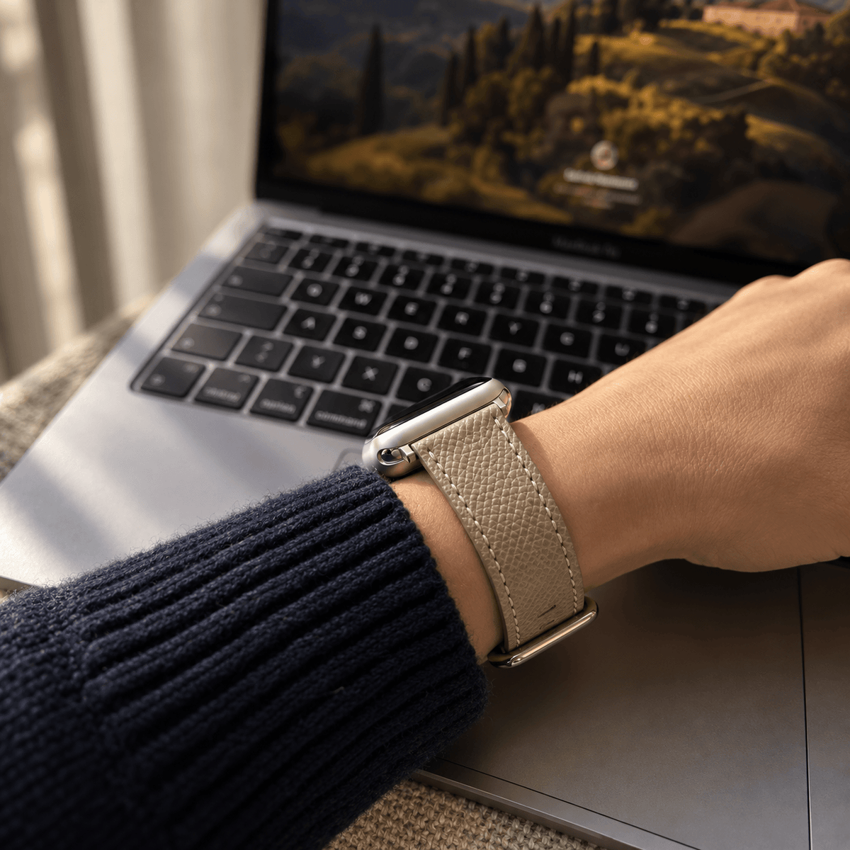 Luxuriöses Apple Watch Lederarmband Damen Cupertino Taupe am Handgelenk vor Laptop, hochwertig, Luxus Apple Watch Armband made in Germany.