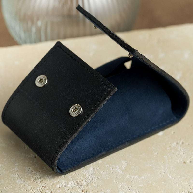 Moodbild eines geöffneten schwarzen Uhrenetuis mit blauem Alcantara-Innenfutter, stilvoll präsentiert auf einer Marmorplatte. Das luxuriöse Design und die hochwertigen Materialien bieten sicheren Schutz und eine elegante Aufbewahrung für Armbanduhren.