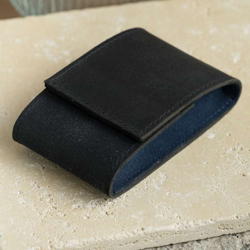 Moodbild eines schwarzen Uhrenetuis mit blauem Alcantara-Innenfutter, stilvoll platziert auf einer Marmorplatte. Luxuriöses Design und hochwertige Materialien für die elegante Präsentation und Aufbewahrung von Armbanduhren.