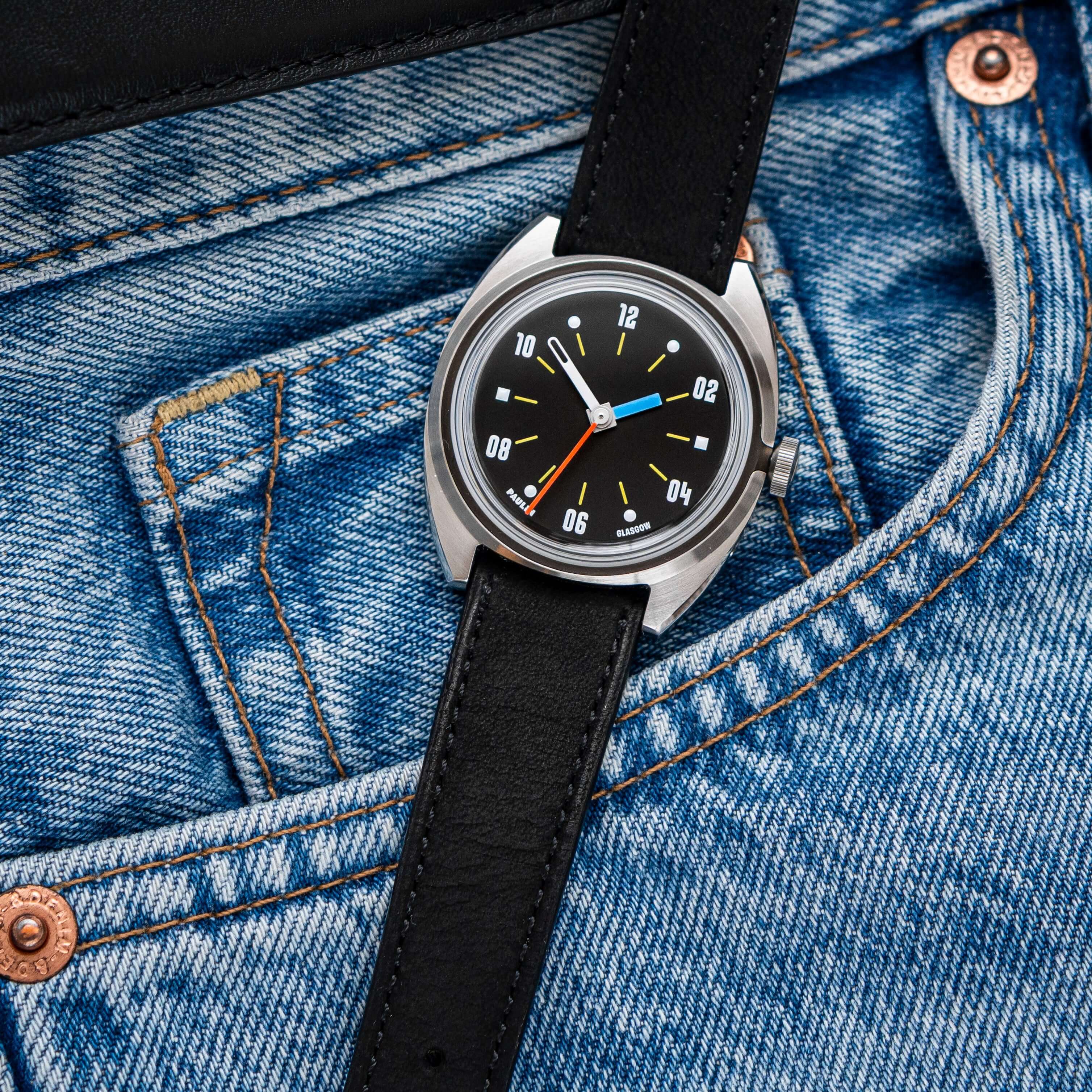 Mountain Bear – Uhrenarmband aus Nubukleder im Vintage-Stil an einer Jeans mit grauem Ziffernblatt.