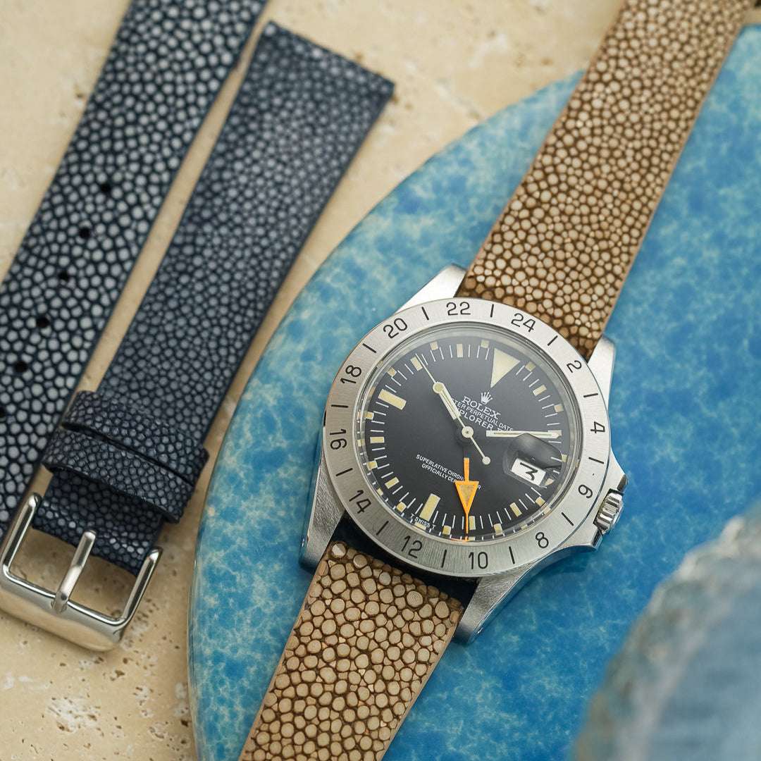 Rolex Explorer 2 aus dem Jahr 1974 mit oranger 24-Stunden-Hand an einem hellbraunen Uhrenarmband, dunkelblaues Perlrochenband danebenliegend, eleganter Vintage-Stil