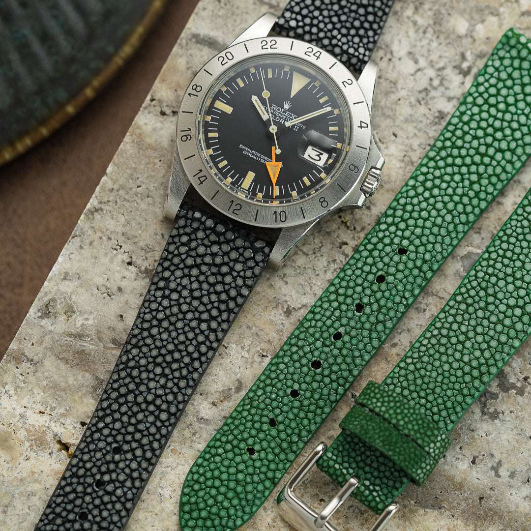 Rolex Explorer 2 aus dem Jahr 1974 mit oranger 24-Stunden-Hand, präsentiert neben einem schwarzen und einem hellgrünen Uhrenarmband aus echtem Perlrochenleder