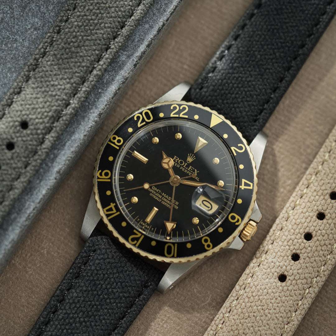 Rolex Oyster Perpetual in Schwarz-Gold an einem schwarzen 20 mm Canvas-Uhrenarmband, sportlich-eleganter Look