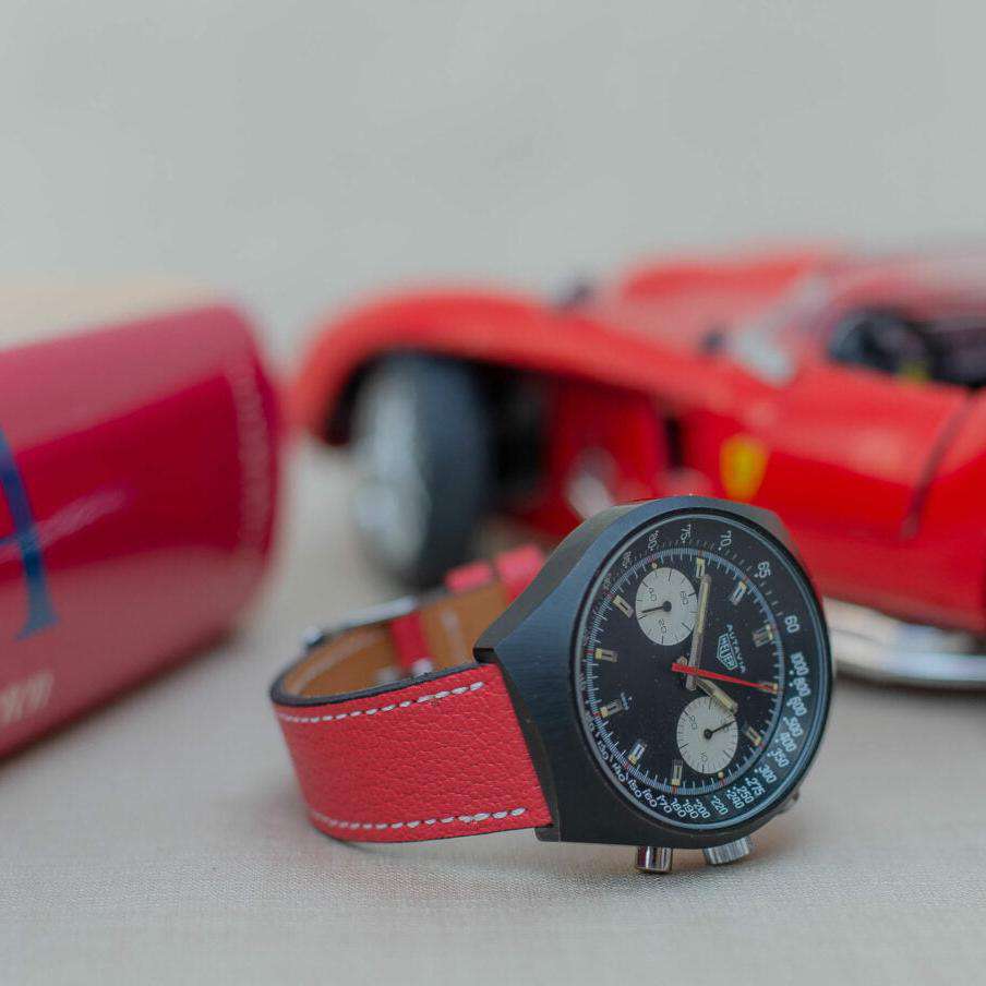 Seitlich fotografiertes rotes Ziegenlederarmband an einer Heuer Autavia, das sportlichen Stil und erstklassigen Komfort bietet