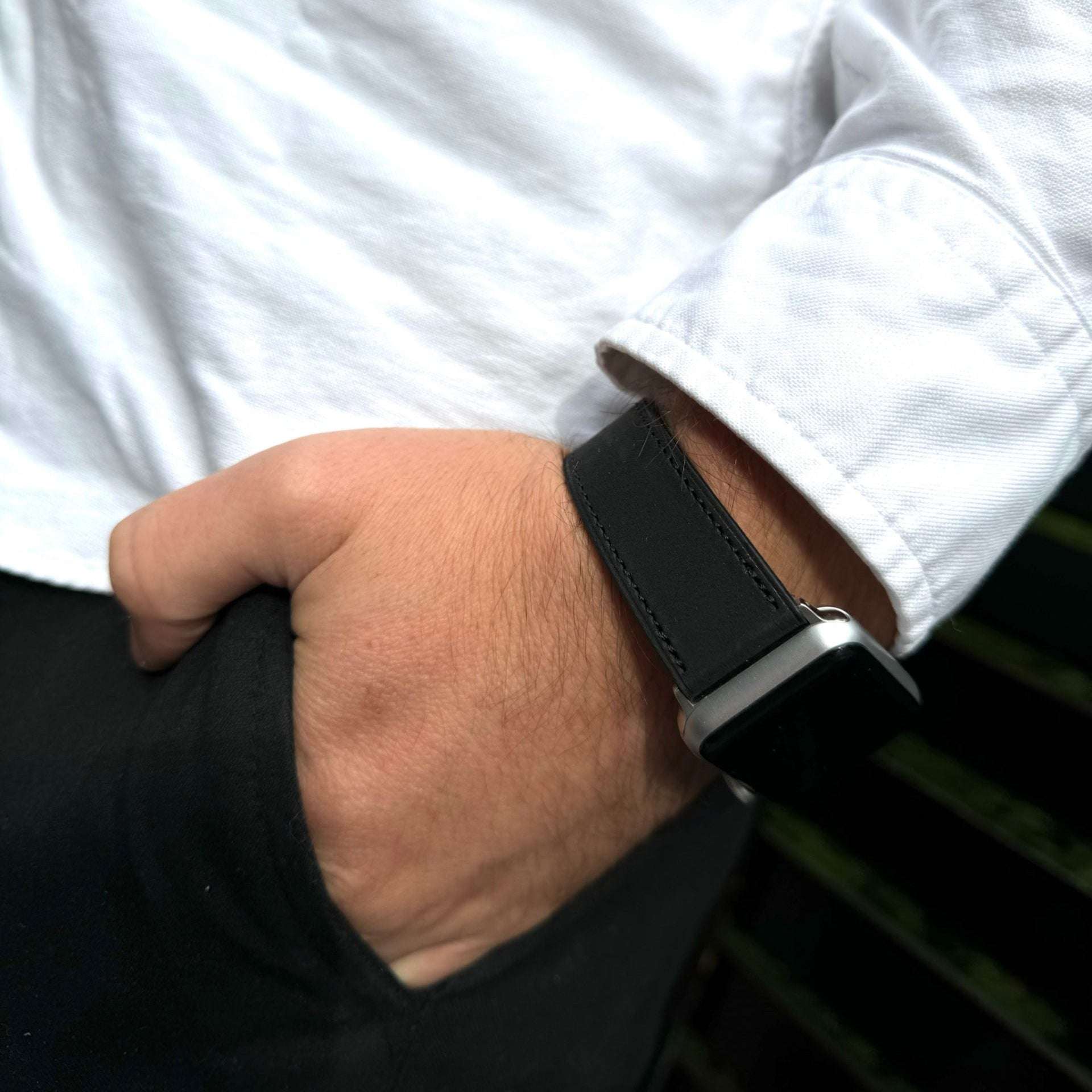 Schwarzes Nubukleder-Armband für Apple Watch am Handgelenk – Stilvolle Kombination mit schwarzer Hose und weißem Hemd im Hintergrund